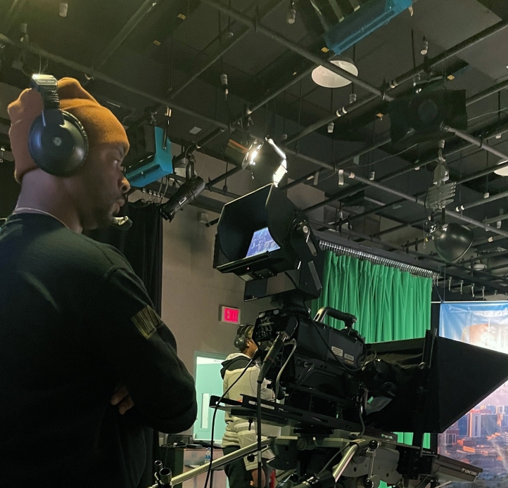 Student wearing headphones looks into video camera